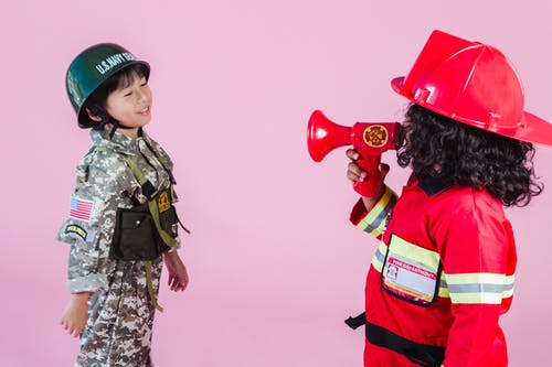 拿着红色心形气球的绿色和棕色伪装制服的女人 · 免费素材图片