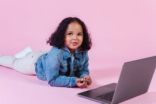 蓝色牛仔夹克和白色的裤子，坐在地板上使用macbook的女孩 · 免费素材图片