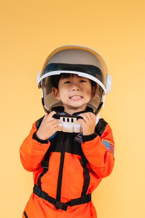 橙色和黑色拉链外套穿白色头盔的男孩 · 免费素材图片