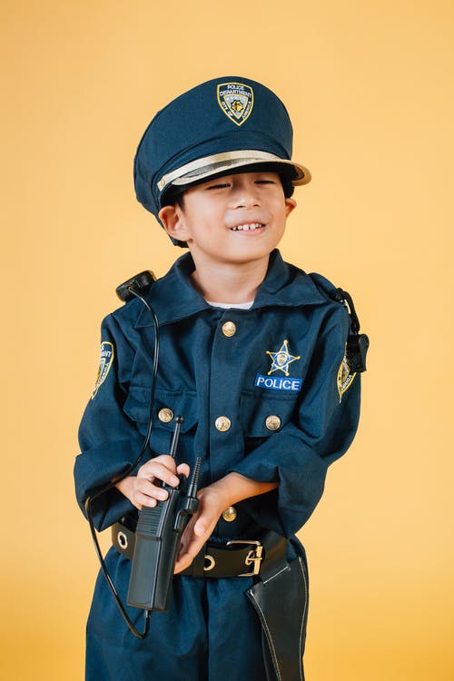 拿着黑色步枪的蓝色警察制服的男孩 · 免费素材图片