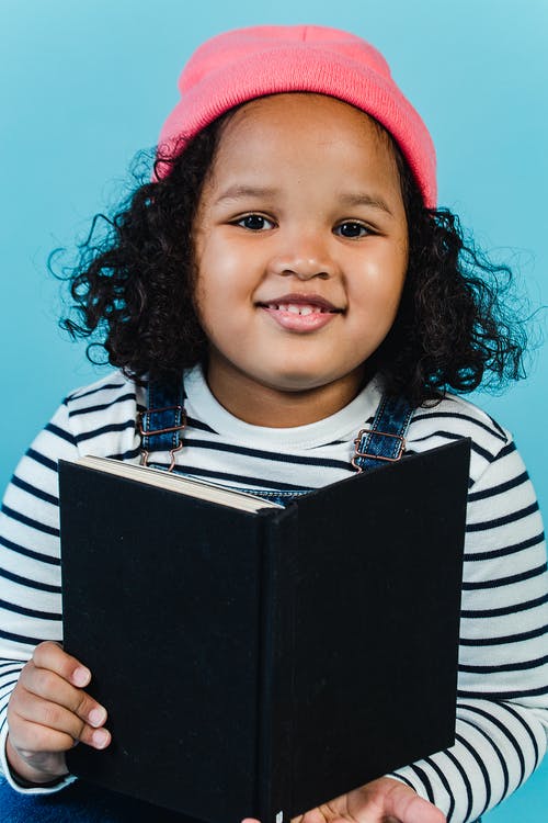 拿着黑皮书的白色和黑色条纹长袖衬衫的女孩 · 免费素材图片