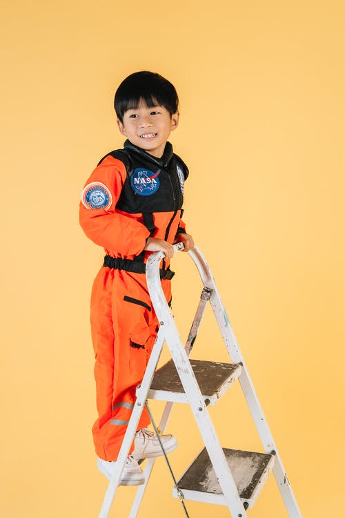 站在梯子上的橙色和黑色外套的男孩 · 免费素材图片