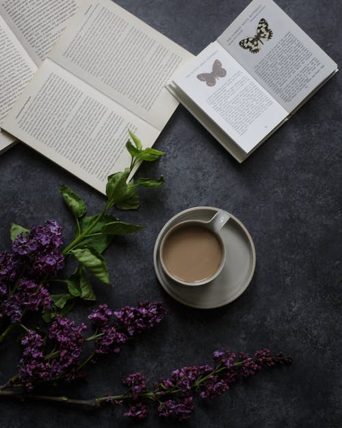 杯咖啡，靠近书和花 · 免费素材图片