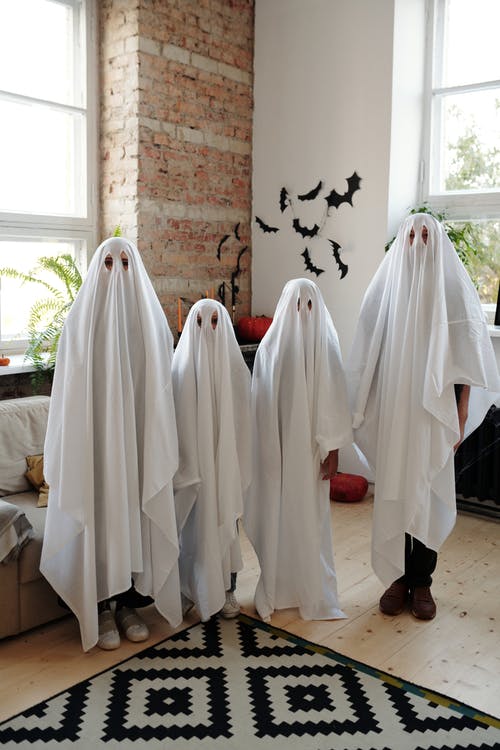 一家人站在客厅里穿着白色的万圣节服装 · 免费素材图片