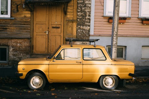 黄色的复古车停在老建筑外 · 免费素材图片