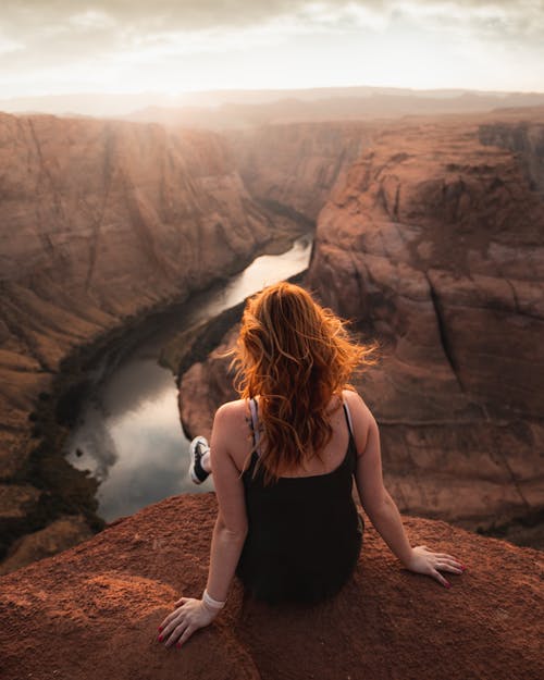 黑色背心坐在棕色岩石上的女人 · 免费素材图片