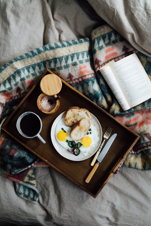 在床上的书附近的托盘上吃早餐 · 免费素材图片