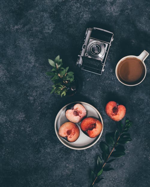 杯咖啡，水果和相机附近 · 免费素材图片