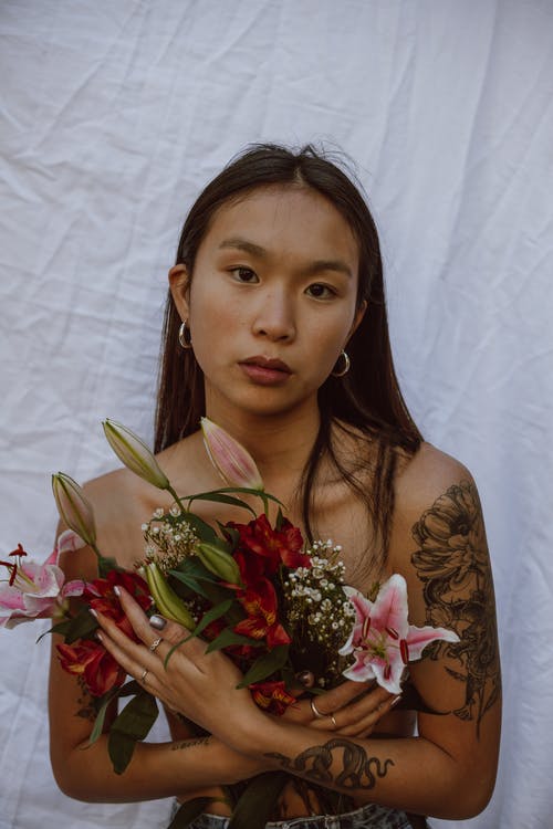 束鲜花的诱人的年轻裸照亚洲女性覆盖乳房 · 免费素材图片