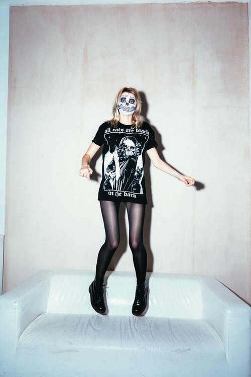 从白色的沙发上跳下来的黑色圆领t恤的女人 · 免费素材图片