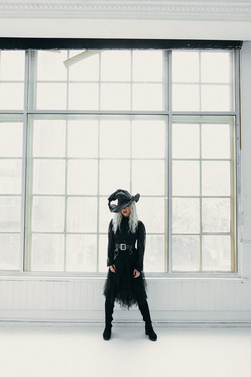 黑色女巫服装站在窗户旁边的女人 · 免费素材图片