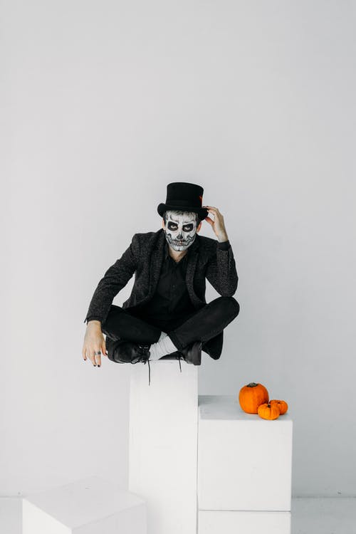 穿黑夹克和黑帽子坐在白盒子上的男人 · 免费素材图片