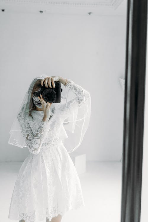 拿着黑色的单反相机的白色花蕾丝婚纱的女人 · 免费素材图片