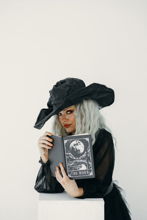 拿着一本黑书的女巫服装的女人 · 免费素材图片