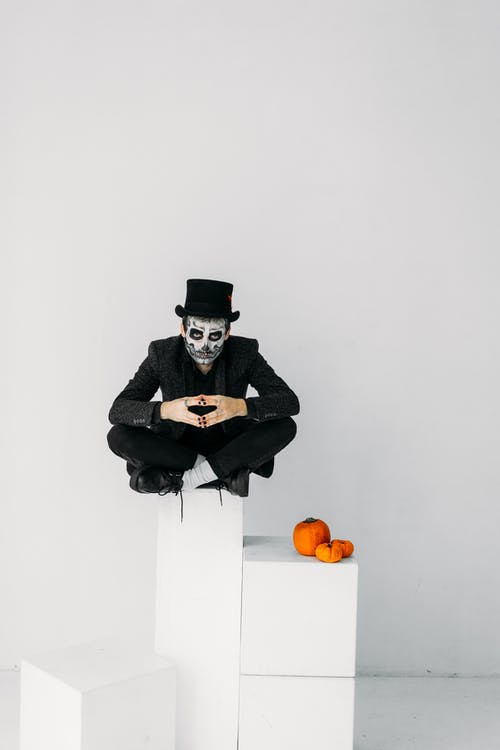 黑大衣和黑帽子坐在白盒子上的男人 · 免费素材图片