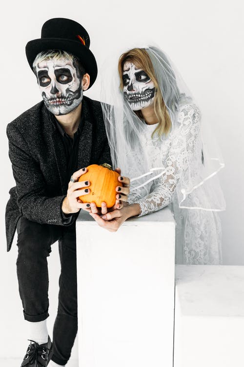男人和女人抱着南瓜的骷髅面漆 · 免费素材图片