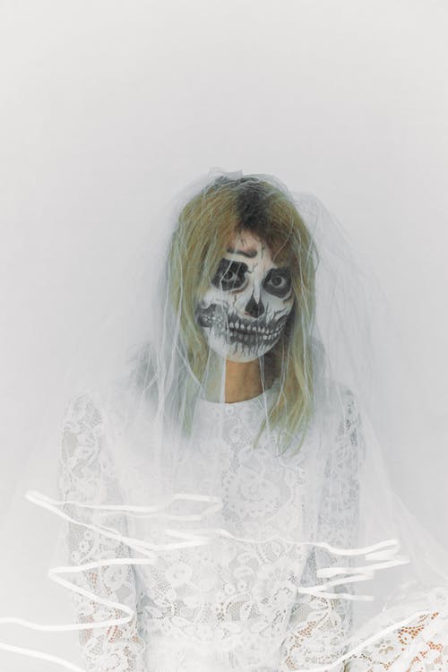 白色蕾丝连衣裙和头骨面漆的女人 · 免费素材图片