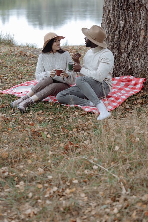灰色毛衣的女人坐在绿草地上的红色和白色纺织 · 免费素材图片
