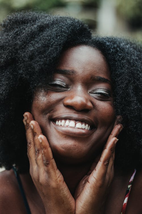 高兴的黑人妇女，抚摸脸颊 · 免费素材图片