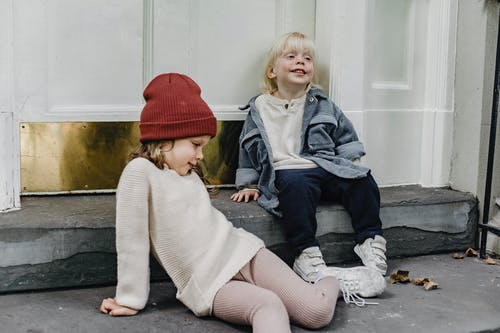 2个女孩坐在灰色的水泥地板上 · 免费素材图片