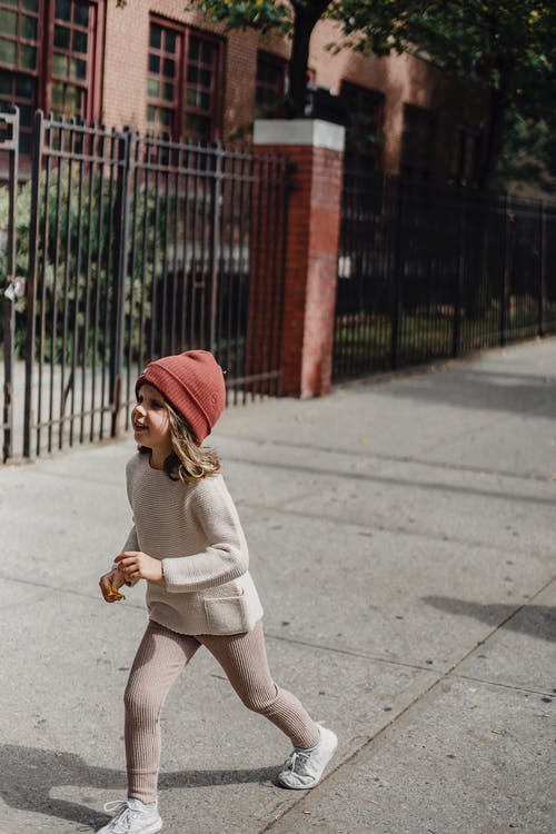 白色毛衣和红色针织帽在人行道上行走的女人 · 免费素材图片