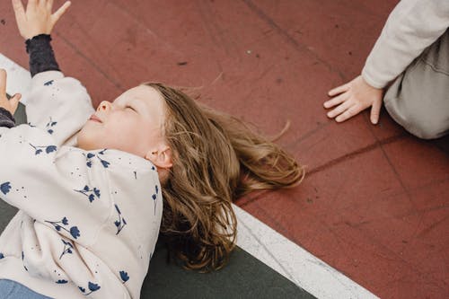 躺在红色的水泥地板上的白色和蓝色的星星印花衬衫的女人 · 免费素材图片
