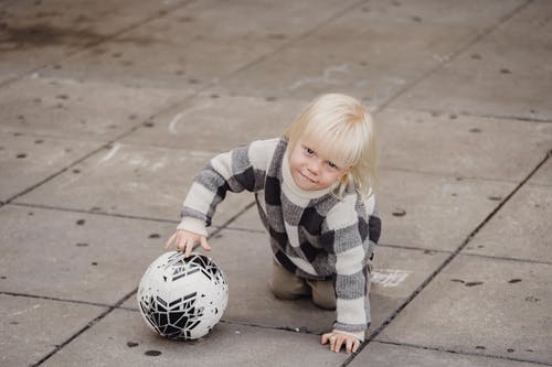 黑色和白色条纹长袖衬衫踢足球的女孩 · 免费素材图片