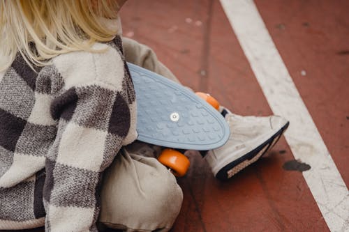 坐在棕色混凝土地板上的灰色和黑色外套的女人 · 免费素材图片