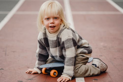 坐在地板上的灰色和白色毛衣的女孩 · 免费素材图片