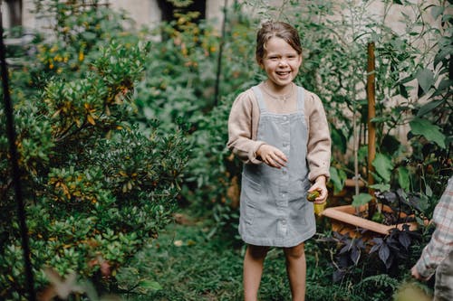 站在绿色的植物附近的灰色长袖连衣裙的女孩 · 免费素材图片