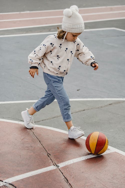 蓝色和白色的圆点毛衣和蓝色牛仔牛仔裤打篮球的男孩 · 免费素材图片