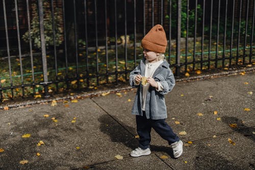 棕色针织帽和灰色夹克站在灰色的混凝土路面上的孩子 · 免费素材图片