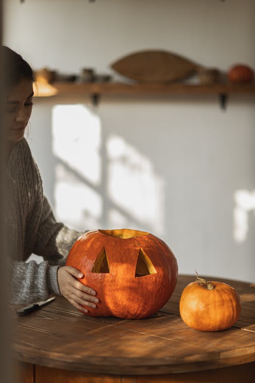 拿着杰克o灯笼的灰色长袖衬衫的女人 · 免费素材图片