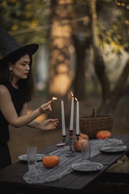 巫婆服装在桌上点燃蜡烛的女人 · 免费素材图片