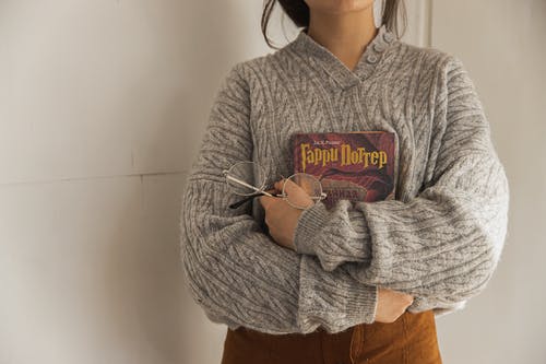 拿着一本书的灰色毛衣的女人 · 免费素材图片