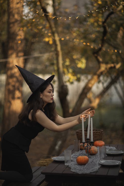 黑色的连衣裙和黑色的帽子，点燃蜡烛的女人 · 免费素材图片