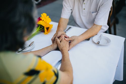 老夫妇手牵着手在桌子上 · 免费素材图片