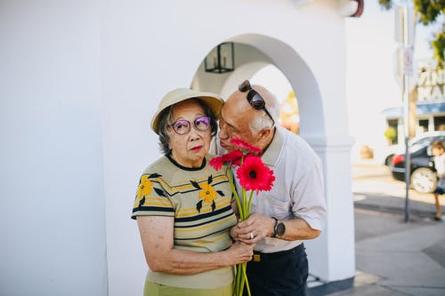 老人在给一束鲜花时亲吻她的妻子 · 免费素材图片