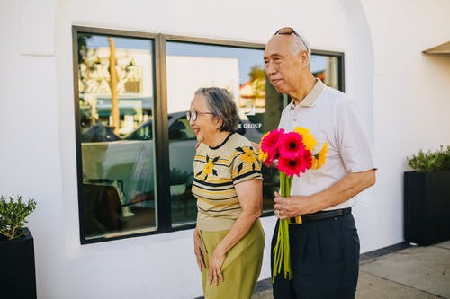 老人与妻子散步时手捧花 · 免费素材图片