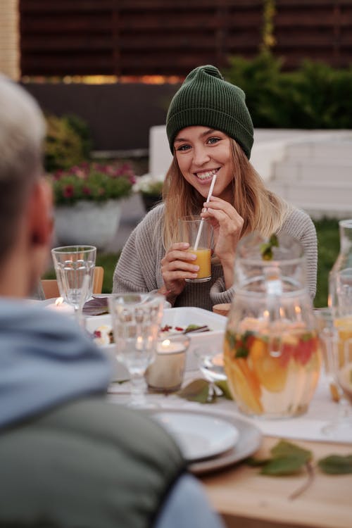 从清晰的水杯喝水的绿色针织帽的女人 · 免费素材图片