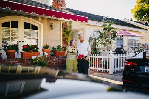 老年夫妇站在房子外面 · 免费素材图片