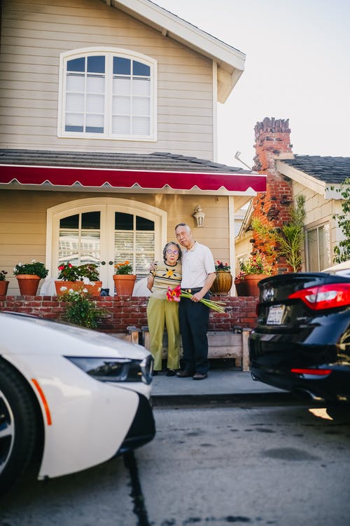 老年夫妇站在他们的房子外面 · 免费素材图片