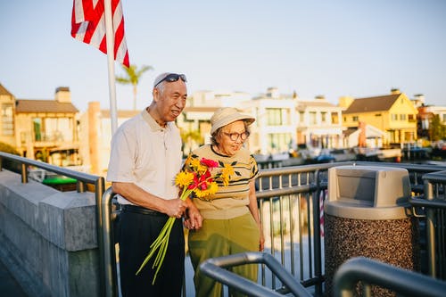 老年夫妇手牵着鲜花花束 · 免费素材图片