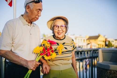 老夫妇手牵着手，手捧花 · 免费素材图片