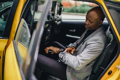 检查在手表的严肃的黑人商人时间在出租汽车 · 免费素材图片