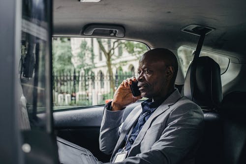 严重的黑人谈到汽车的智能手机 · 免费素材图片