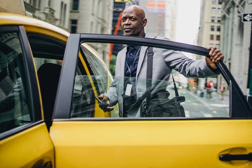 在现代城市中打开出租车门的黑人商人 · 免费素材图片