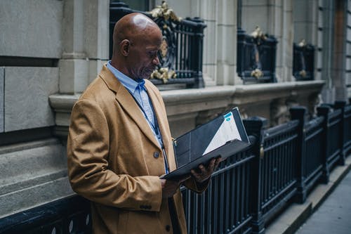 经验丰富的黑人律师在大街上阅读文件 · 免费素材图片