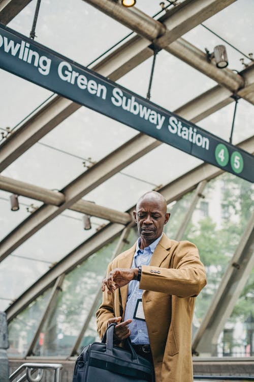 男人看着他的手表在地铁站上 · 免费素材图片