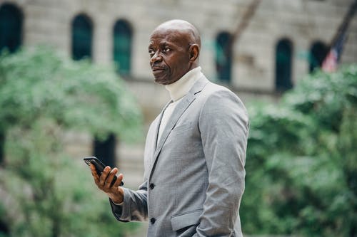严重的黑人男子，与大街上的智能手机 · 免费素材图片